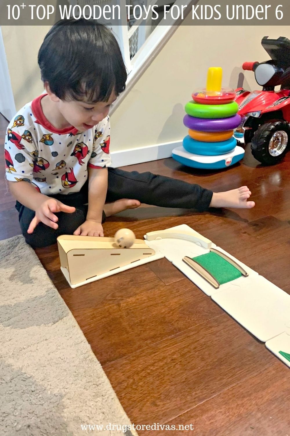 A boy playing with a wooden track and the words "10+ Top Wooden Toys For Kids Under 6" digitally written above him.