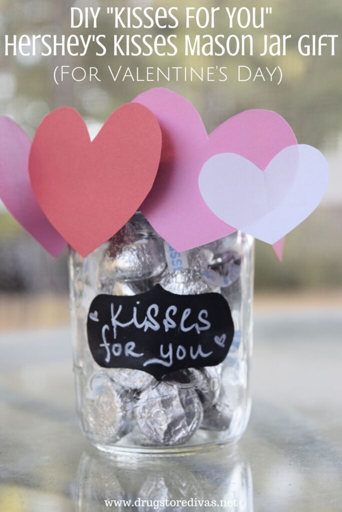 A Hershey's Kisses filled mason jar with paper hearts around the top at and the words "DIY Kisses For You Hershey's Kisses Mason Jar Craft (For Valentine's Day)" digitally written on top.