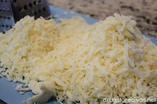 A bunch of shredded cheese on a blue cutting board.