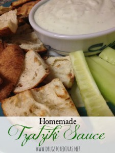 Tzatziki sauce in a bowl surrounded by pita chips and cucumbers.