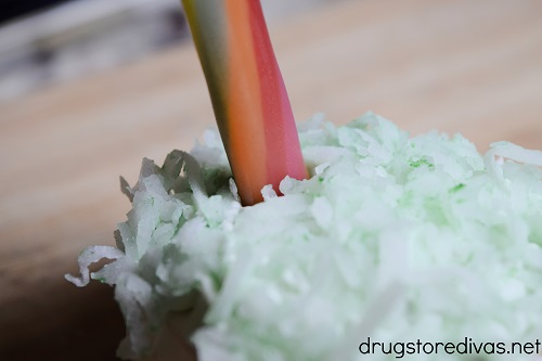 A candy rope stuck into green coconut on top of a mini cake.