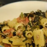 Sausage, rigatoni pasta, kale, and tomatoes in a bowl with the words 