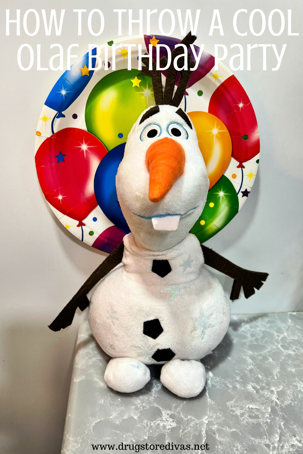 A stuffed animal of Olay, from Frozen, with a birthday paper plate behind his head and the words 