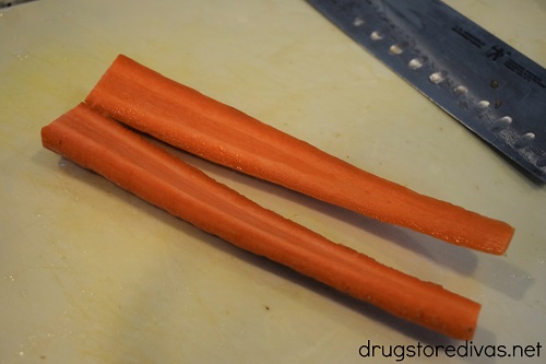 Carrots, cut in half, on a cutting board.