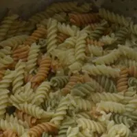 Tri-colored spiral pasta in a colander with the words 