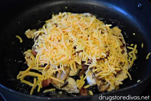Chicken breast tenderloins, topped with bacon and cheese, in a pan.