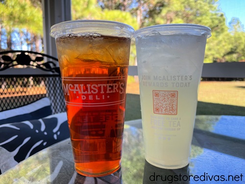 An iced tea and a lemonade from McAlister's Deli side by side on a glass table.