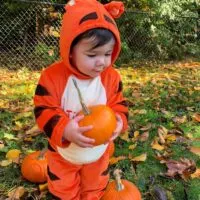 A baby dressed in a Tigger costume with the words 