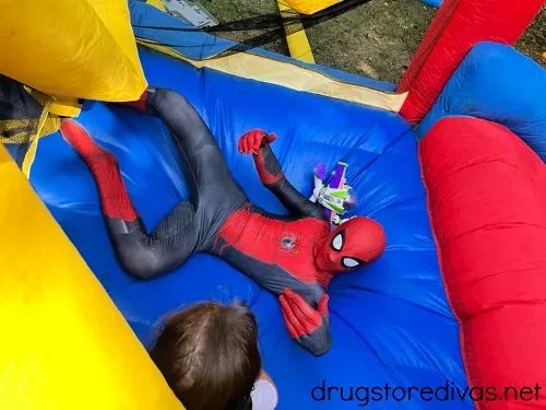 A person dressed in a Spiderman costume in a bounce house.