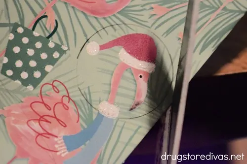 A flamingo-themed Christmas card being cut with a pair of scissors.