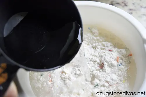 Water pouring into cake mix in a bowl.