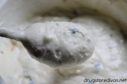 Funfetti cake mix in a spoon above a bowl of funfetti cake mix.