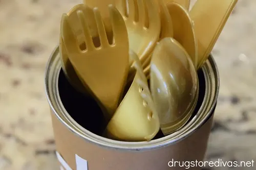 Gold flatware in a tin can that looks like a football.