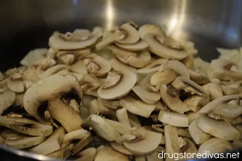 Sliced mushrooms in a silver skillet.