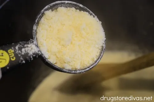 Parmesan cheese in a measuring cup about to be poured into a large pot.