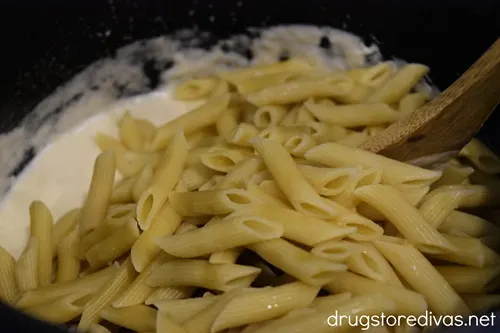 White sauce and cooked penne pasta in a pot.