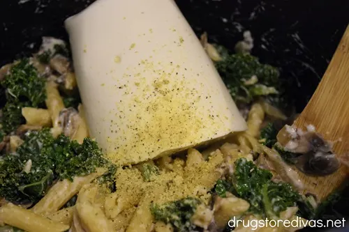 Ricotta cheese and seasoning on top of pasta and vegetables in a pot.
