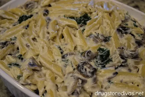 Pasta, mushrooms, and kale in a cream sauce in a casserole pan.
