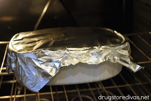 A casserole pan with foil on top in an oven.