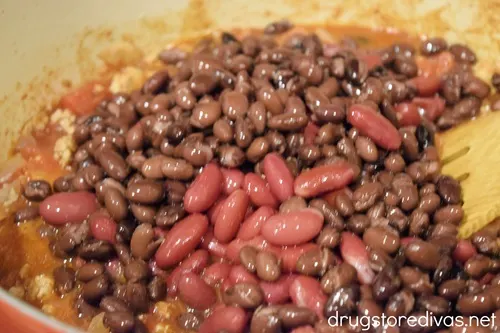Red and black beans on top of ground meat in a Dutch oven.