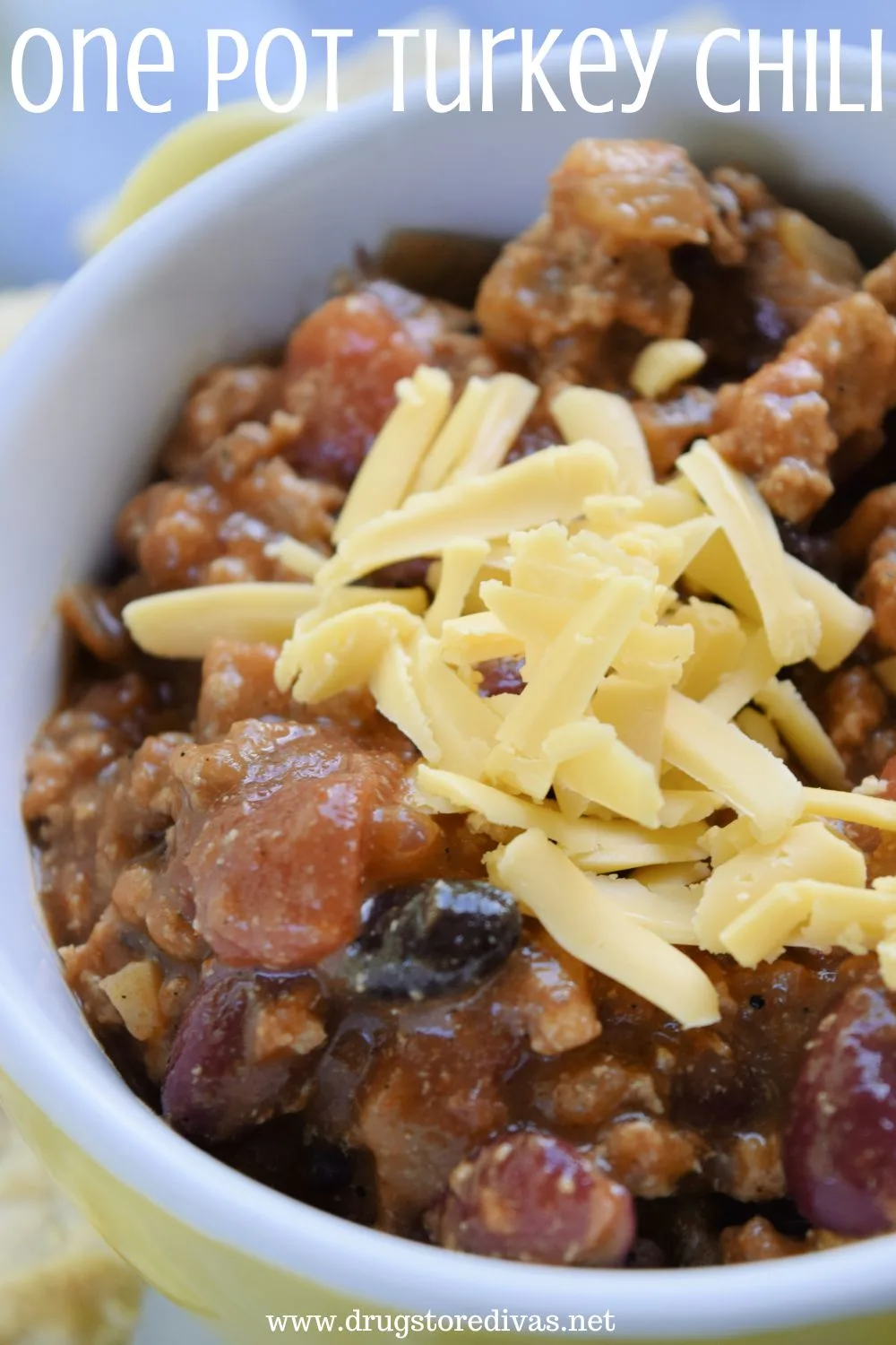 Chili in a yellow bowl with yellow cheese on top and the words 