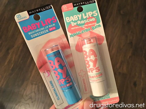 A hand holding two packs of Maybelline Baby Lips lip balm.