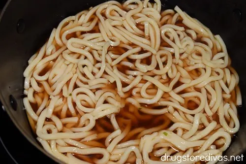 Udon noodles in a dark broth in a pot.