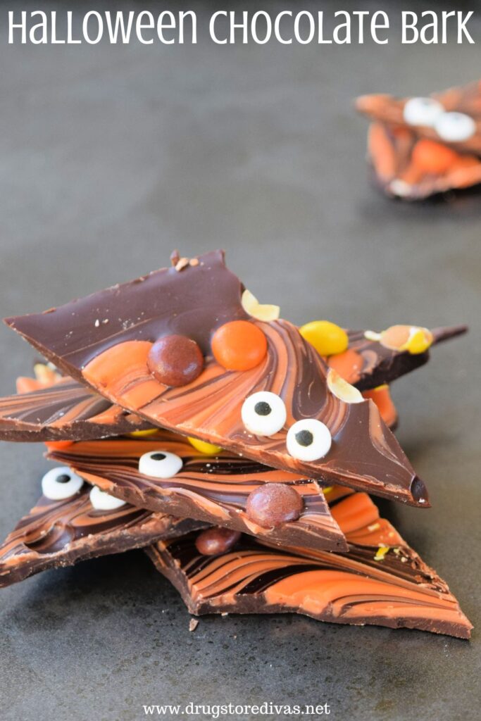 Pieces of brown and orange chocolate bark, with candy eyes and Reese's pieces in it, and the words "Halloween Chocolate Bark" digitally written on top.