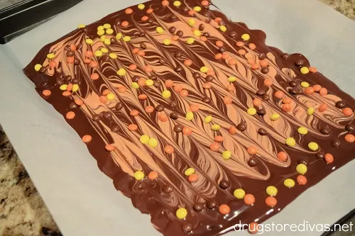 Melted orange and brown chocolate swirled together with Reese's Pieces on top.