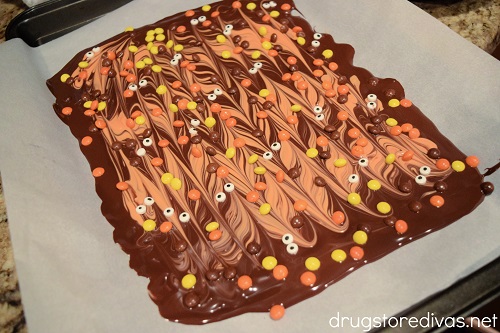 Melted orange and brown chocolate swirled together with Reese's Pieces and candy eyes on top.