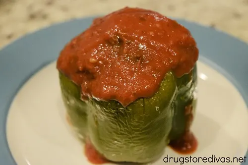 A stuffed green pepper topped with sauce.