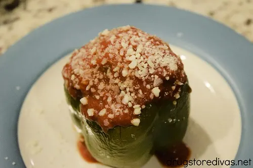 A stuffed green pepper topped with cheese and sauce.