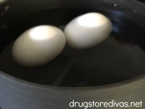 Two eggs submerged in water in a pot.