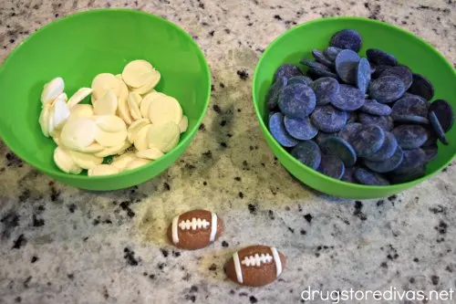 White candy melts and blue candy melts in bowls with two gummy football candies in front of them.