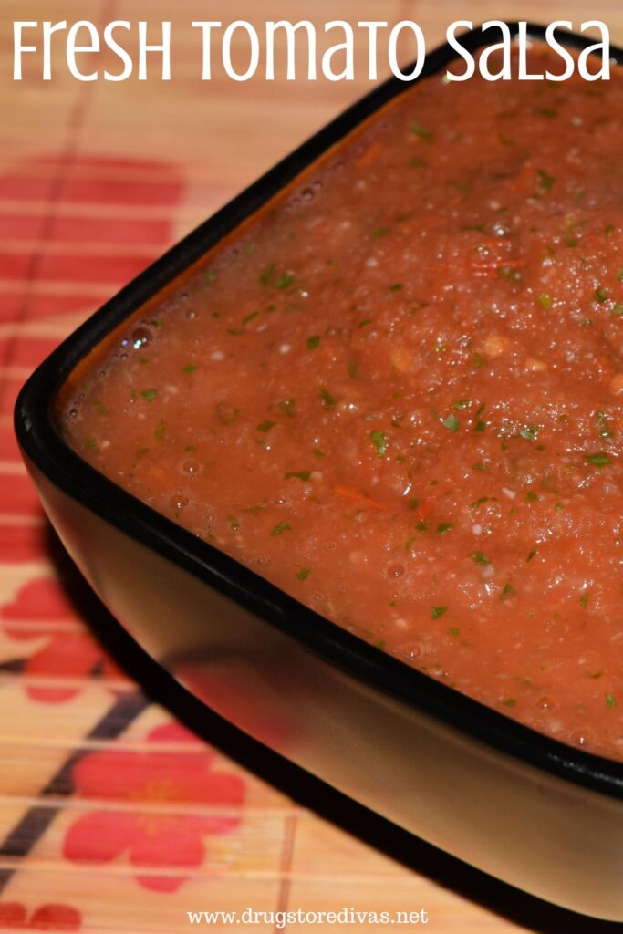 Tomato salsa in a black bowl with the words "Fresh Tomato Salsa" digitally written on top.