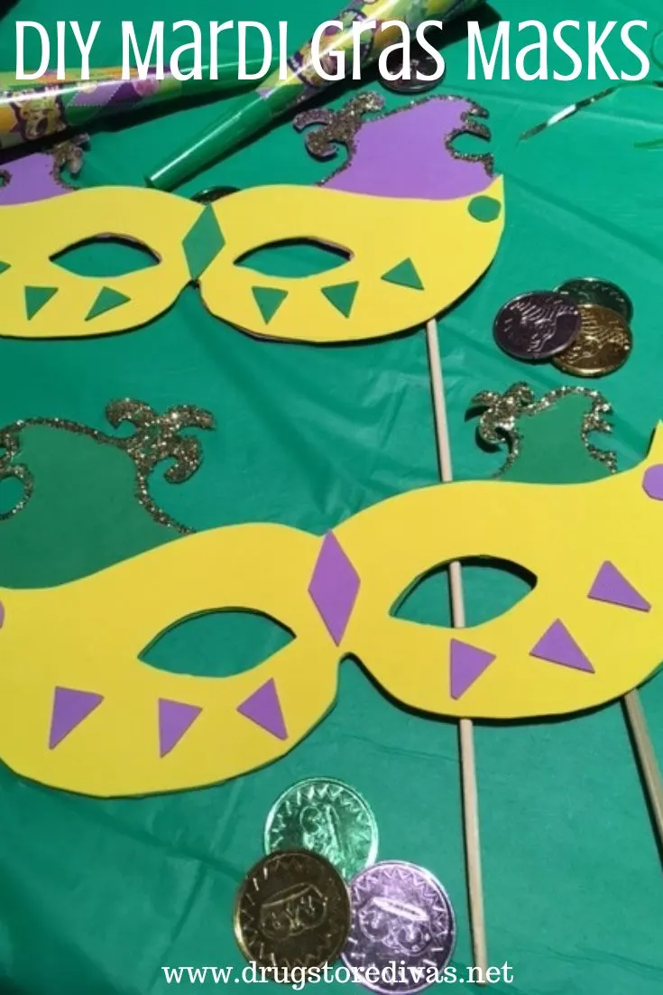 Two homemade foam Mardi Gras masks on a green tablecloth with beads and coins around them and the words 