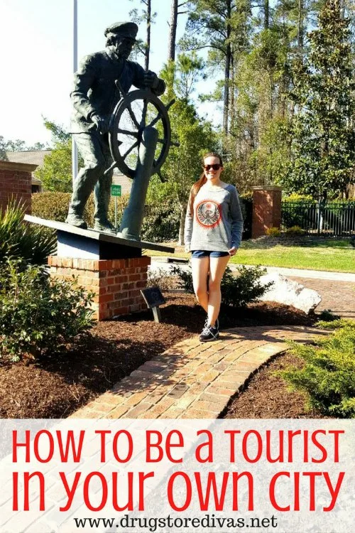 A woman standing in front of a captain statue with the words "How To Be A Tourist In Your Own City" digitally written under it.