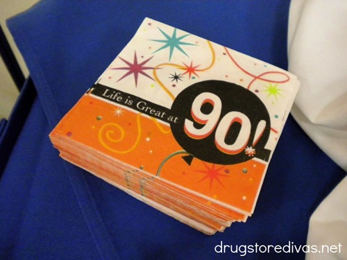 An orange and white birthday napkin that says "Life Is Great at 90!" on it.