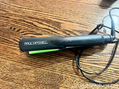 A black flat iron on a wooden table.