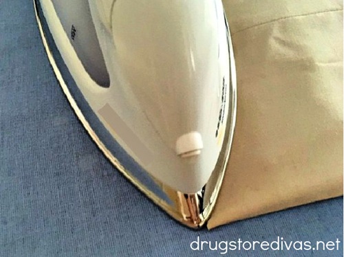 An iron ironing a khaki pair of pants on a blue ironing board.
