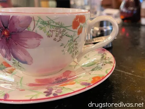 A flowered cup of coffee and matching saucer. 