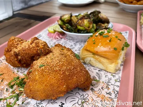 Two pieces of chicken, a honey bun, and brussels sprouts on a tray from Honeymoon Chicken in Washington, DC.