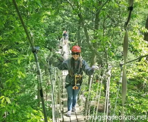 Woman on a bridge on a zipline course.