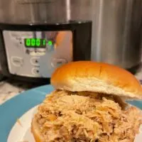Pulled pork sandwich in front of a slow cooker with the words 