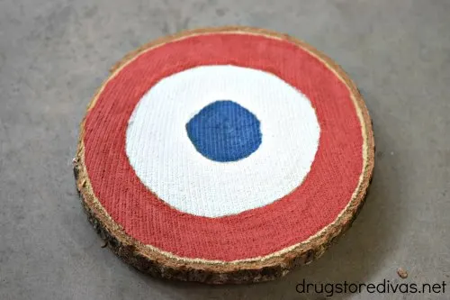 A wooden coaster painted with a red, white, and blue circle.