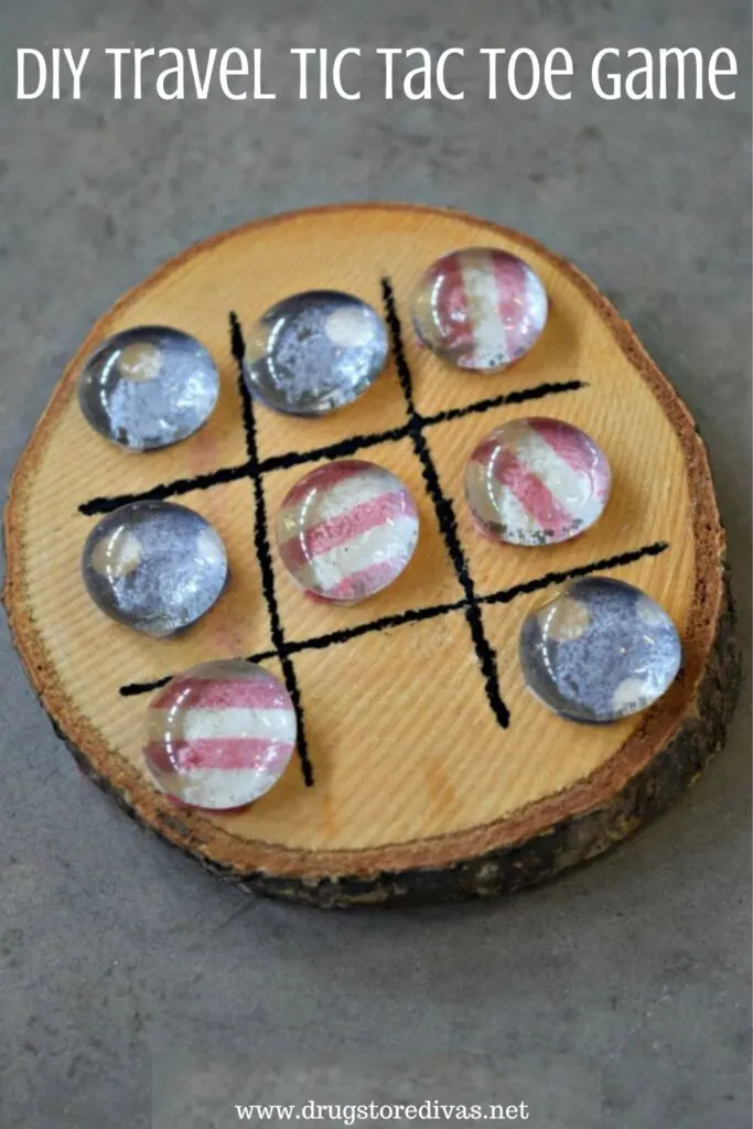 A wooden coaster with a tic tac toe board and pieces on it with the words "DIY Travel Tic Tac Toe Game" digitally written on top.
