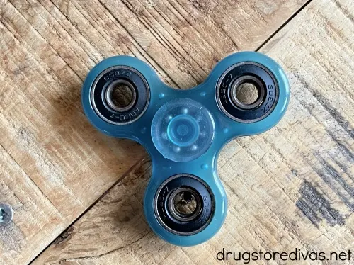 A blue fidget spinner on a wooden background.