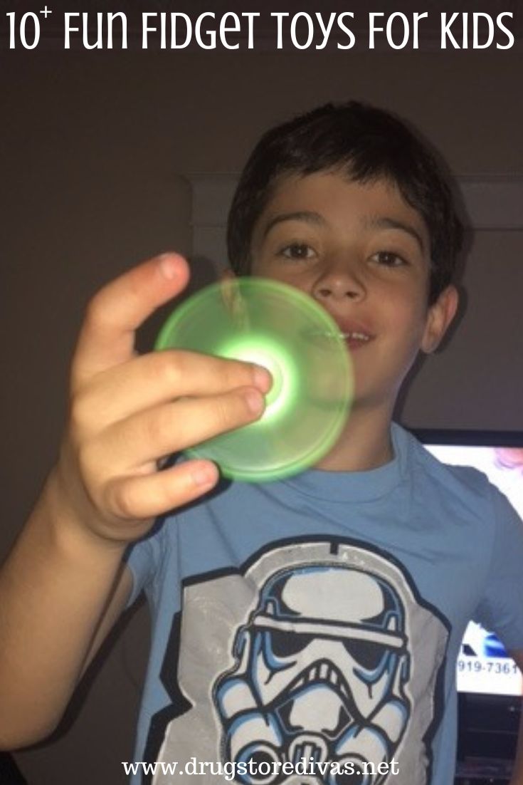 A boy playing with a green fidget spinner with the words 
