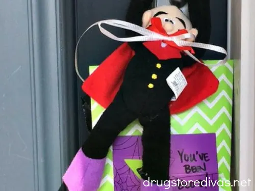 A vampire stuffed doll and a boo bag hanging on a blue door.