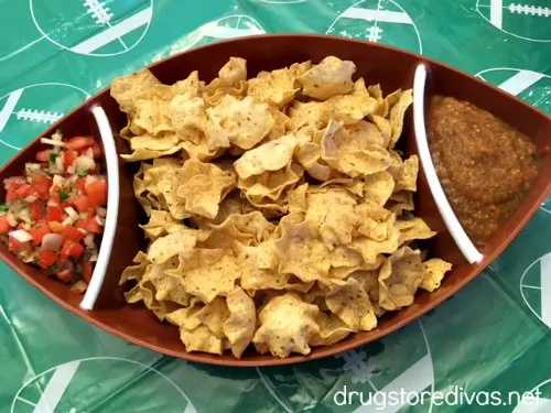 A football-shaped tray filled with tortilla chips and salsa.